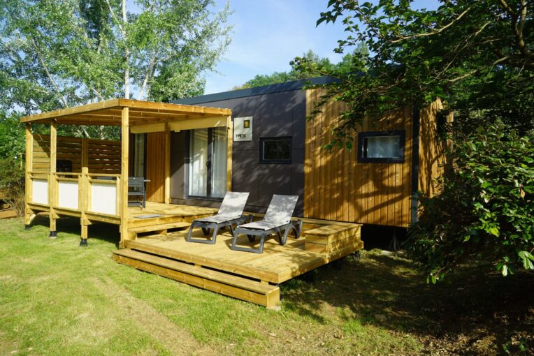 Mobil-home avec terrasse Mobil-home en bois avec terrasse couverte et transats, sur un emplacement engazonné du camping à Sarlat