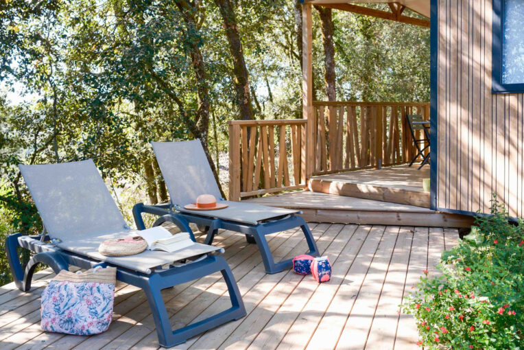Terrasse d'hébergement en surplomb Terrasse en bois d'un hébergement du Domaine Le Montant avec transats, en surplomb des arbres